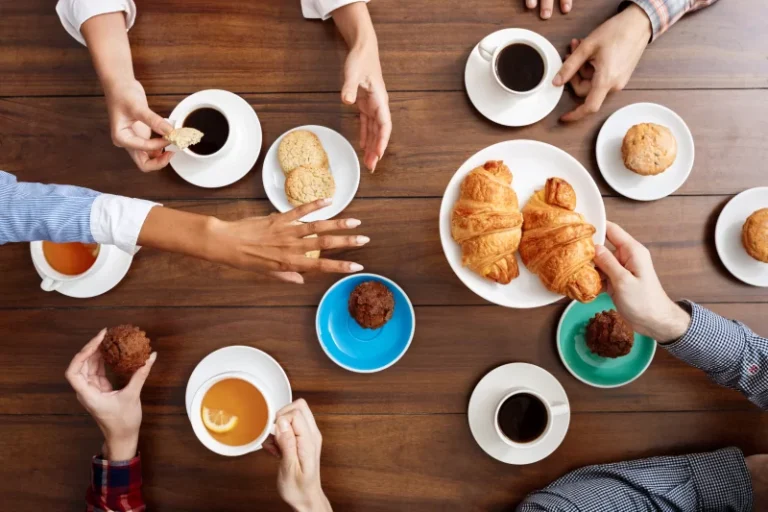 pessoas-maos-na-mesa-de-madeira-com-croissants-e-cafe-800x533-1.webp